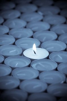 a lit candle sitting in the middle of rows of white plates on top of each other