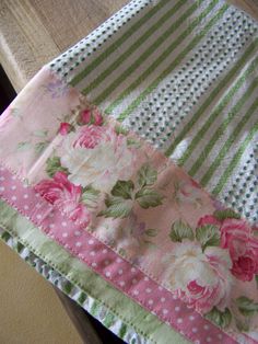 a pink and green flowered table cloth on a wooden table top with polka dots