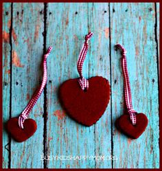 two heart shaped cookies tied to strings on a blue wooden background with the words, valentine's day