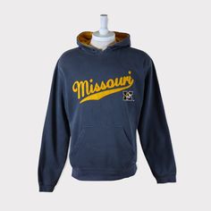 Embroidered Vintage 90s Missouri Tigers (University of Missouri) Football/Baseball/Basketball/Hockey NCAA Hoodie 💯 SATISFACTION AND AUTHENTICITY ⭐ MEASUREMENTS (when laid flat) Size on Tag: M Length: 69cm or 27 inches Armpit to armpit: 57cm or 22.5 inches ⭐ CONDITION 9/10 (Very good) Details: No holes Material: Cotton Color: Gray Brand: J America 🔷 Please give us your phone no. together with address after you purchased. 🔷Please keep in mind that our items are vintage so they may show some sig Cotton Hooded Tops For Fan Gear, Throwback Long Sleeve Hoodie For Fall, Cotton Hooded Top For Fan Merchandise, Varsity Cotton Hoodie With Embroidered Logo, Throwback Fan Merchandise Cotton Sweatshirt, College Hooded Sweatshirt With Kangaroo Pocket, Throwback Cotton Sweatshirt For Fan Merchandise, Vintage Hoodie With Double-lined Hood For Sports, Throwback Cotton Hoodie With Drawstring Hood