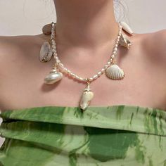 a woman in a green dress wearing a necklace with shells on it