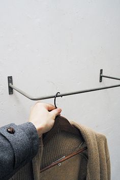 a person holding onto a coat hanger on a wall