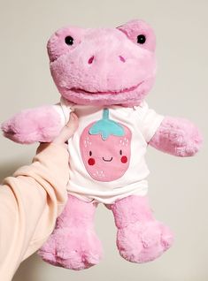 a person holding a pink stuffed animal in their hand