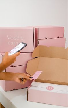 a person holding a cell phone in front of boxes with pink notes on them,