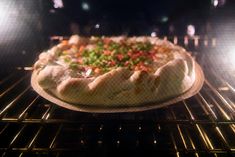 an uncooked pizza sitting in the oven with lots of toppings on it