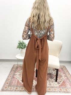 Get ready to lounge in style with the Layla Drawstring Jumpsuit. This mocha brown ribbed knit jumpsuit features a loose fit and adjustable shoulder strap for ultimate comfort. The wide leg design and hidden side seam pockets make it both trendy and functional. Perfect for a day of relaxation or running errands in style. Pairs well with our floral mesh tops! True to size Model is 5'4 and wearing a small 60% Polyester, 35% Rayon, 5% Spandex Cheap Women's Fall Jumpsuits And Rompers, Cheap Jumpsuits And Rompers For Day Out In Fall, Pant Romper With Sweater, Cheap Fall Jumpsuits And Rompers For Day Out, Dolman Sweater Over Jumpsuit, Fall Jumpsuits & Rompers, Modern Bohemian Outfits, Salon Outfits, Style A Jumpsuit