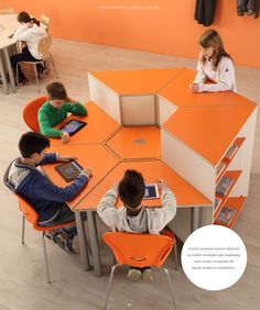 four children sitting at an orange table using their ipads and tablet computers in a classroom