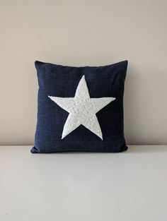 a blue pillow with a white star embroidered on it sitting on top of a table