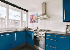 a kitchen with blue cabinets and stainless steel stove top oven in the middle of it