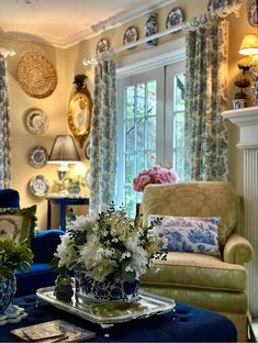 a living room filled with furniture and flowers on top of a blue table covered in plates