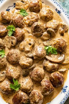 a white plate topped with meatballs covered in gravy and garnished with parsley