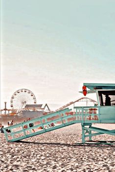 a lifeguard tower sitting on top of a sandy beach next to a ferris wheel