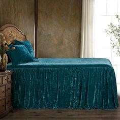 the bed is made with teal colored sheets and pillows, along with two vases filled with flowers