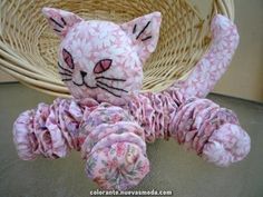 a stuffed cat sitting on top of a table next to a wicker basket filled with yarn