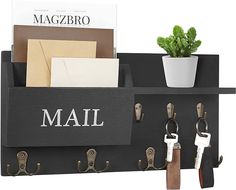 a wall mounted mail holder with keys and other items on it, next to a potted plant