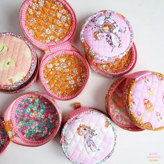 several small pink and orange purses sitting next to each other on a white surface