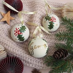 three christmas ornaments with the word germe on them next to pine cones and seashells