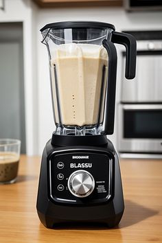 a black blender sitting on top of a wooden table next to a glass container