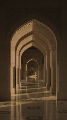 an archway leading into a building with white walls and floor tiles on both sides, in the middle of a long hallway