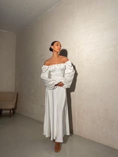 a woman in a white dress standing next to a wall