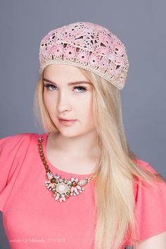 a woman with long blonde hair wearing a pink shirt and a crochet hat