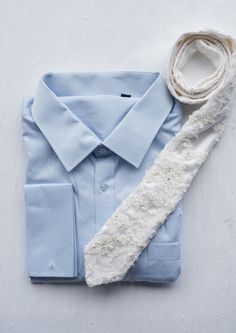 a blue shirt with white lace on it and a scarf laying next to the collar