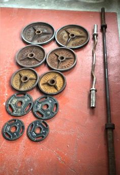 an assortment of different types of metal objects on a red surface next to a wrench and screwdriver