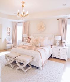 a white bedroom with a chandelier hanging from the ceiling and a large bed