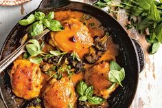 a skillet filled with meat and vegetables on top of a table