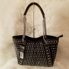 The Front And Sides Of This Dramatic Handbag Are Literally Covered In Alternating Columns Of Sparkling Rhinestones And Round, Polished Metal Stud. To Further Set The Tone, Feature Panels Are Trimmed With Square Metal Studs. The Effect Is Visually Stunning. Dual Carrying Straps 10 Inch Drop Length Zippered Top Opening Made Of Simulated Leather Construction Zippered Back Pocket Fully Lined Interior Includes Inside Zipper Pocket And Cell Phone Pouch Silver Toned Hardware. Silver Leather Shoulder Bag As Fashion Accessory, Silver Leather Bags For Fashion, Party Leather Bags With Rhinestones, Silver Leather Bag With Rhinestones, Leather Party Bag With Silver Accents, Party Leather Bag With Silver Accents, Leather Evening Bags With Silver Accents, Rectangular Shoulder Bag With Rhinestone Rivets For Everyday Use, Evening Leather Bags With Silver Accents