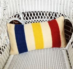 a white wicker chair with a colorful striped pillow on it's backrest