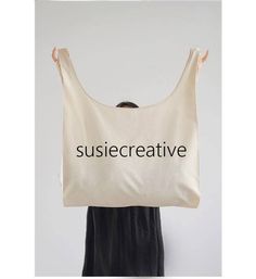 a woman holding up a bag with the word susiecreative printed on it