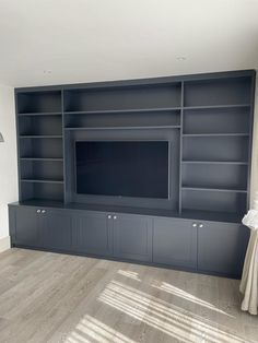 an empty living room with built - in bookshelves and a television on the wall