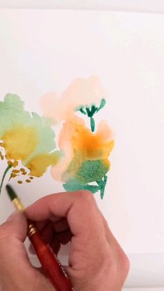 someone is painting flowers with watercolors on paper