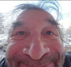 a man with long hair and beard smiling at the camera