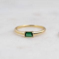 two gold rings one with a green stone and the other has a black diamond on it