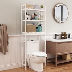 a white toilet sitting next to a bathroom sink under a mirror on top of a wooden shelf