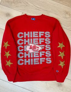 A vintage Champion Kansas City Chiefs graphic sweatshirt with a worn-in look and gold sparkly rhinestone stars down the sleeves. Heavy weight fabric. Small mark on back. Hand wash only Hang to dry Sizing: X-LargeMeasurements:Length: 26.5 inPit to pit width laying flat: 23 inSleeve length: 23 inShoulder to shoulder length: 20.5 in localE vintage pieces are pre-owned, one-of-a-kind pieces that are hand picked by us and reworked. This means that some may have small marks and a worn-in look. Any mar Long Sleeve Cotton Sweatshirt With Glitter Print, Cotton Glitter Print Long Sleeve Sweatshirt, Chicago Bulls Sweatshirt, University Of Kansas, Kc Chiefs, Vintage Type, Vintage Champion, Kansas City Chiefs, Vintage Sweatshirt