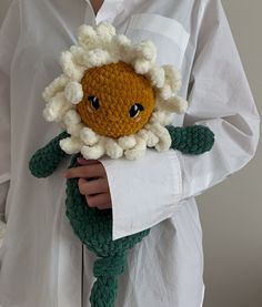 a person wearing a white shirt holding a crocheted stuffed animal in their hands