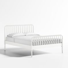 a white bed with two pillows on top of the headboard and foot board, in front of a white wall