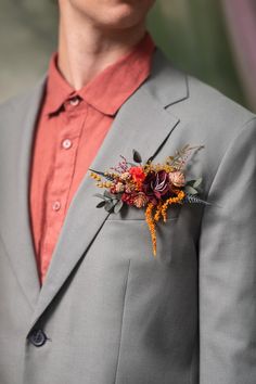 a man in a gray suit with a red shirt and flower boutonniere