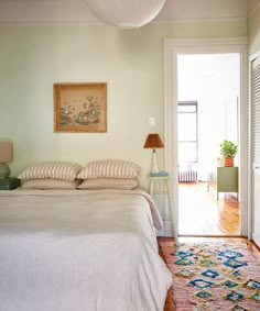 a white bed sitting next to a doorway with a lamp on top of the headboard