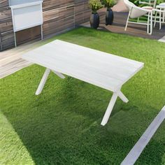 a white table sitting on top of a green grass covered field next to a wooden fence