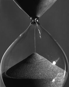 black and white photograph of an hourglass with sand running through it's sides