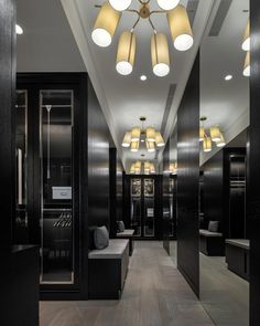 an empty hallway with several lights hanging from the ceiling and two benches on either side