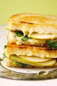 a grilled cheese sandwich with spinach and apple slices on a glass platter