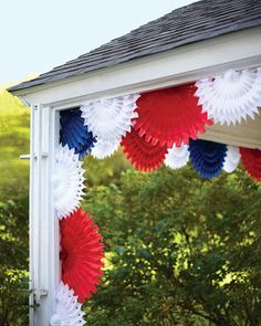 red, white and blue paper fans are hanging from the side of a gazebo