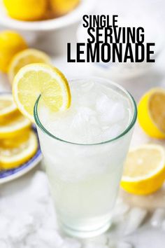 a glass filled with lemonade sitting on top of a table next to sliced lemons