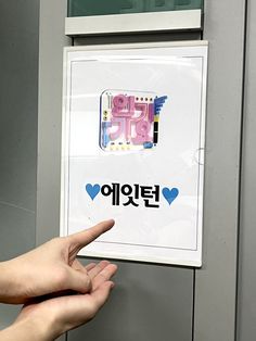 a hand pointing at a sign with korean writing on it and hearts in the background