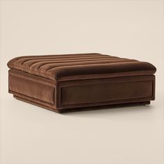 a brown ottoman sitting on top of a white floor